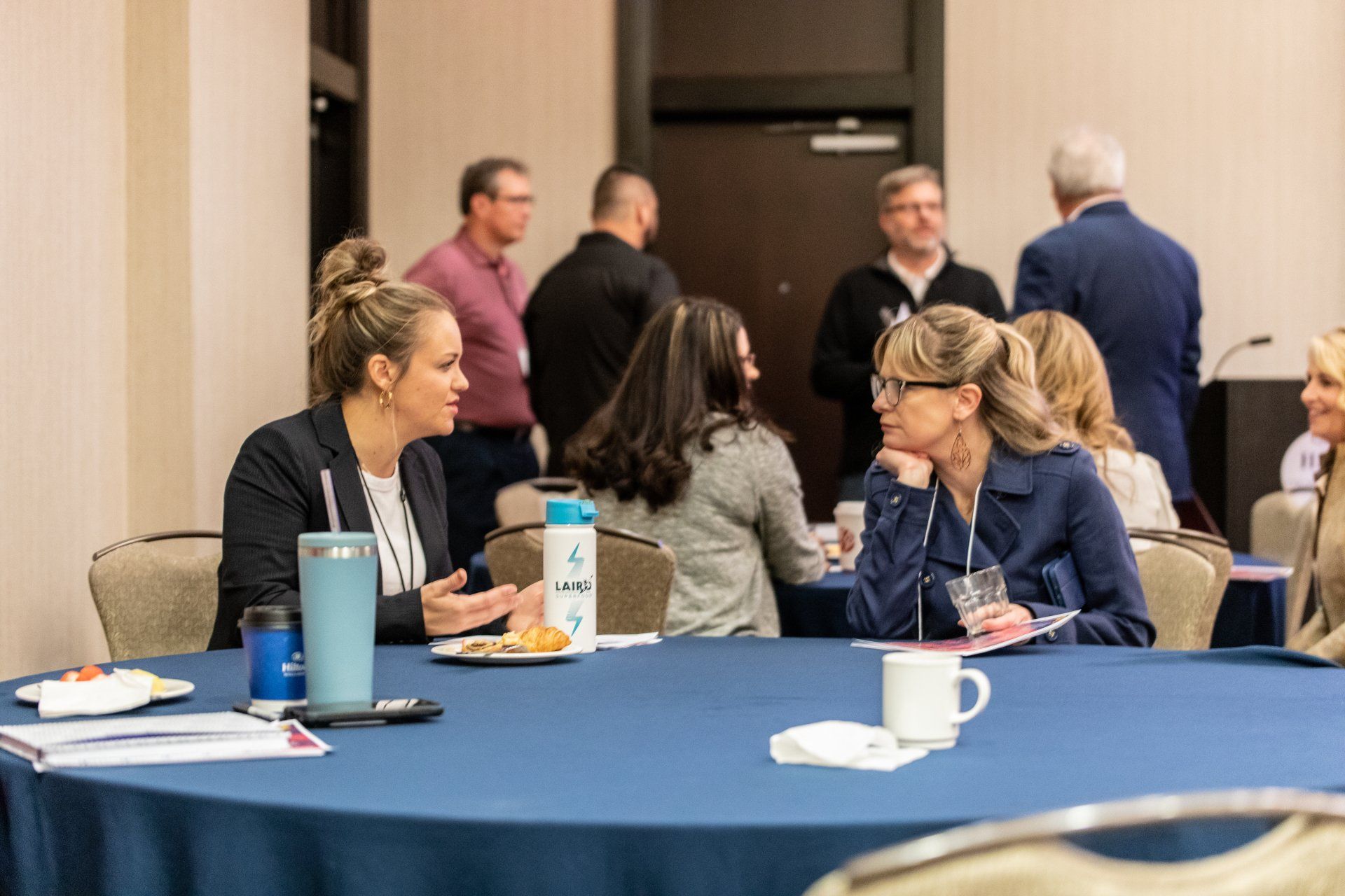 A group of people are sitting at a table talking to each other.