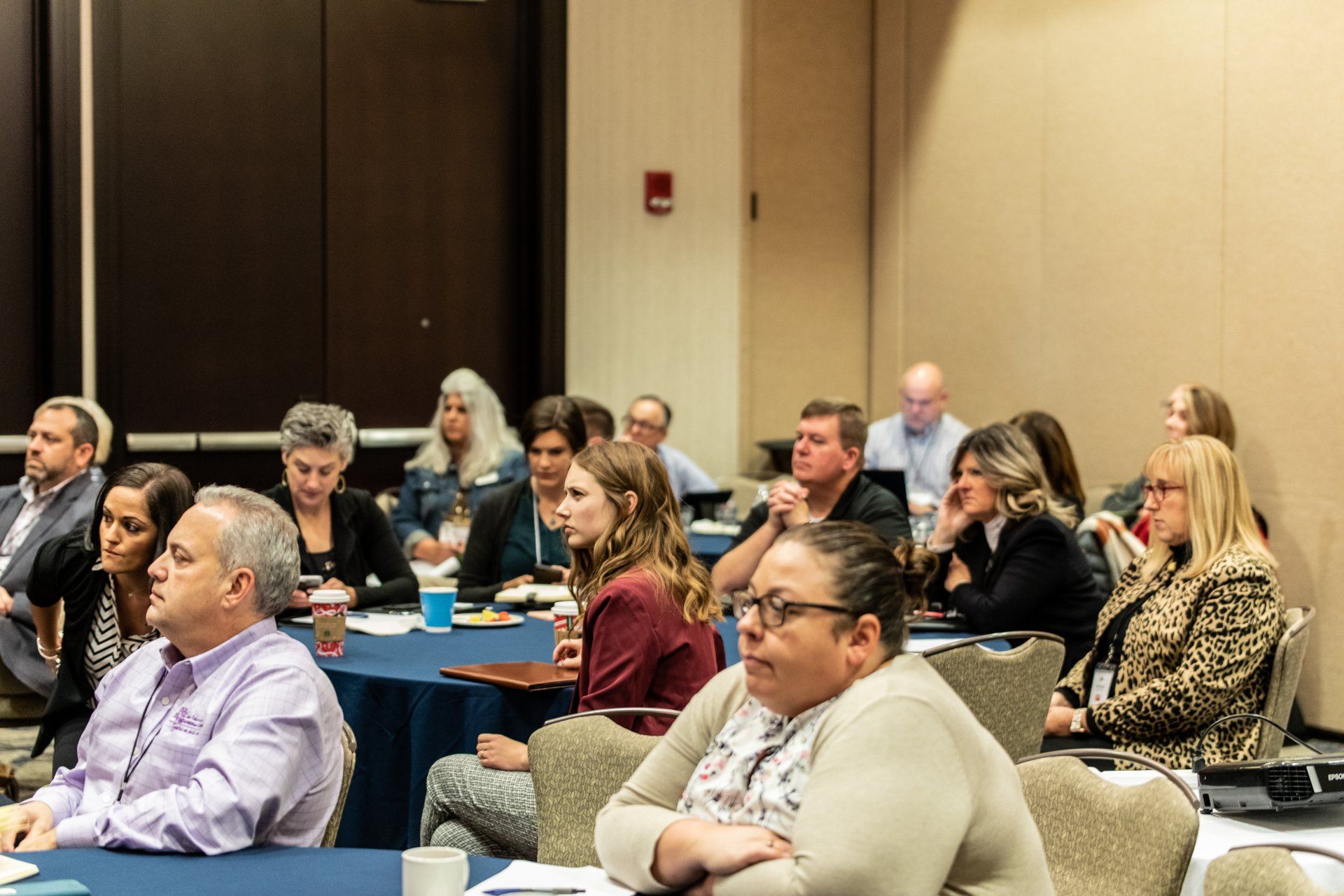A group of people are sitting at tables in a conference room.