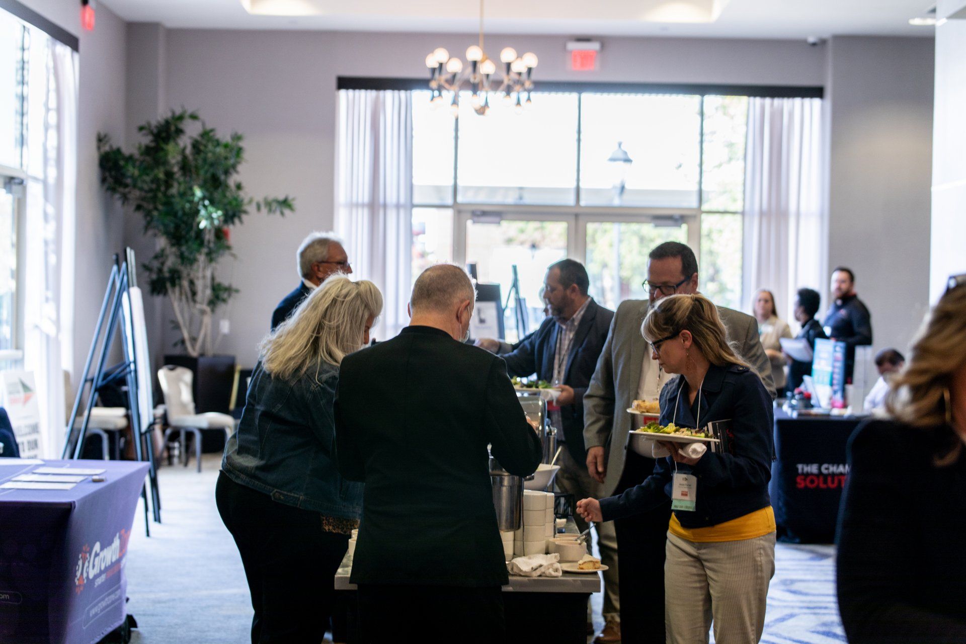 A group of people are standing around a table eating food.