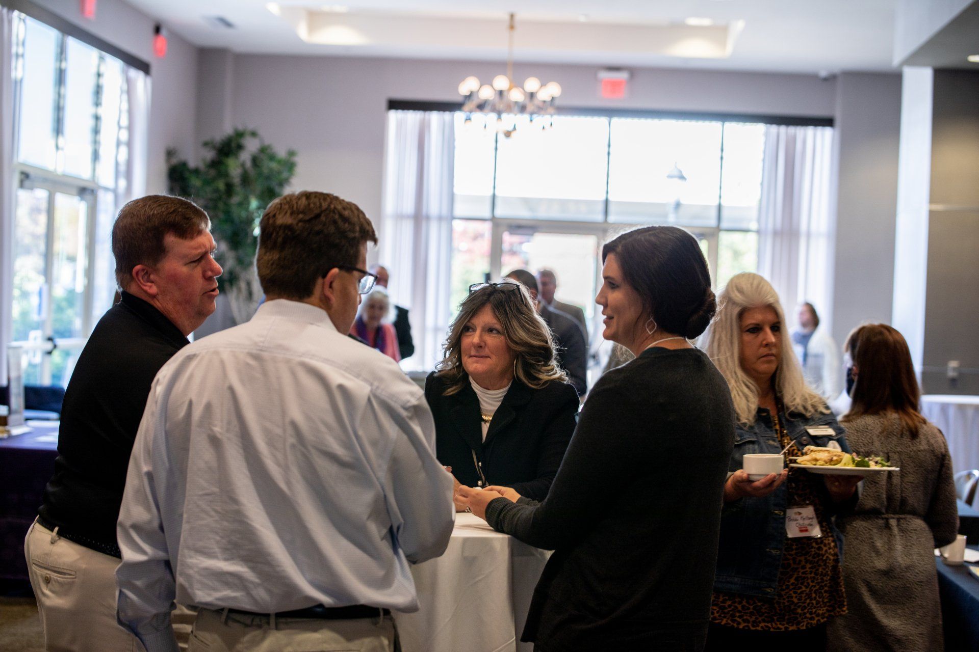 A group of people are standing in a room talking to each other.