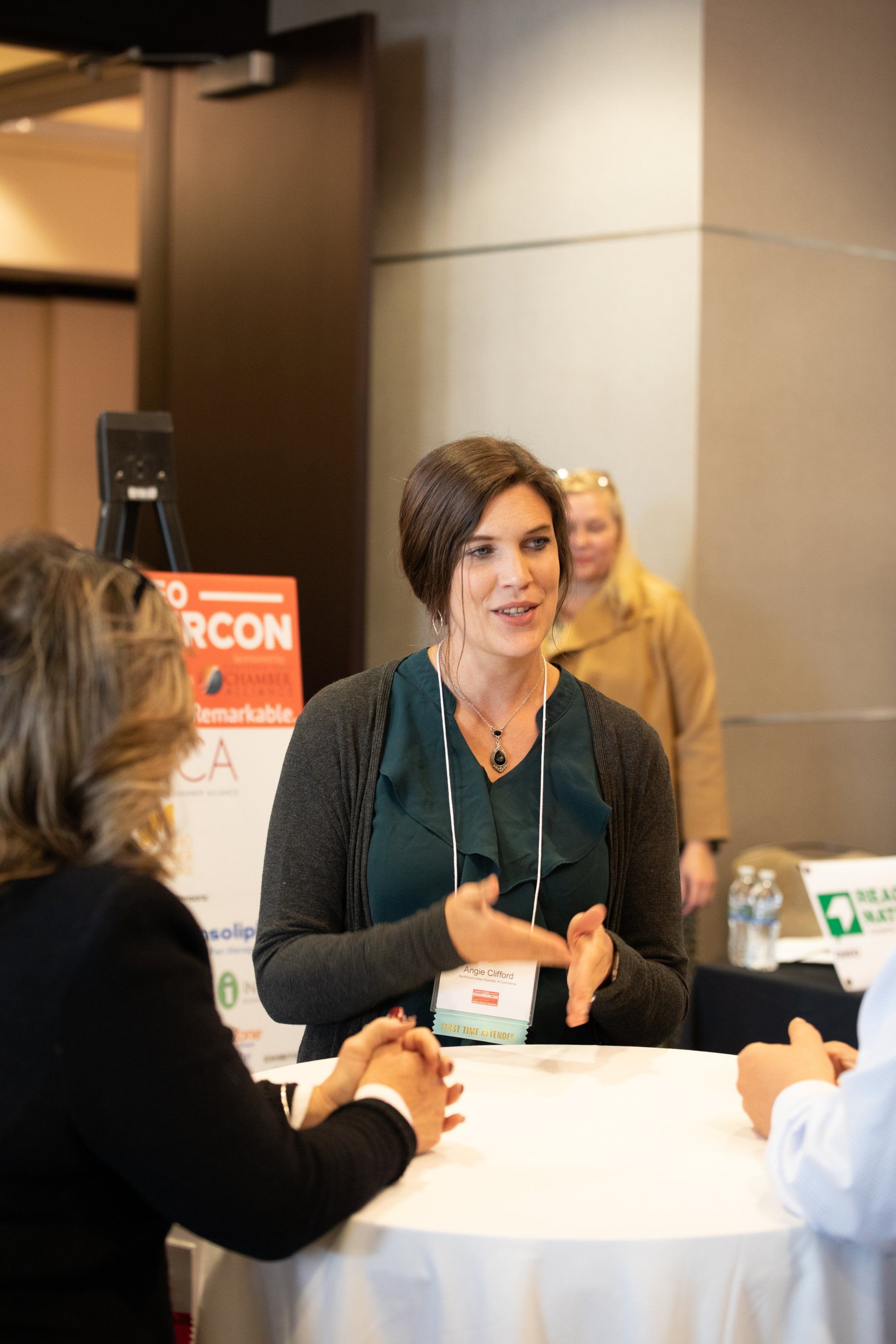 A woman is sitting at a table talking to two other women.
