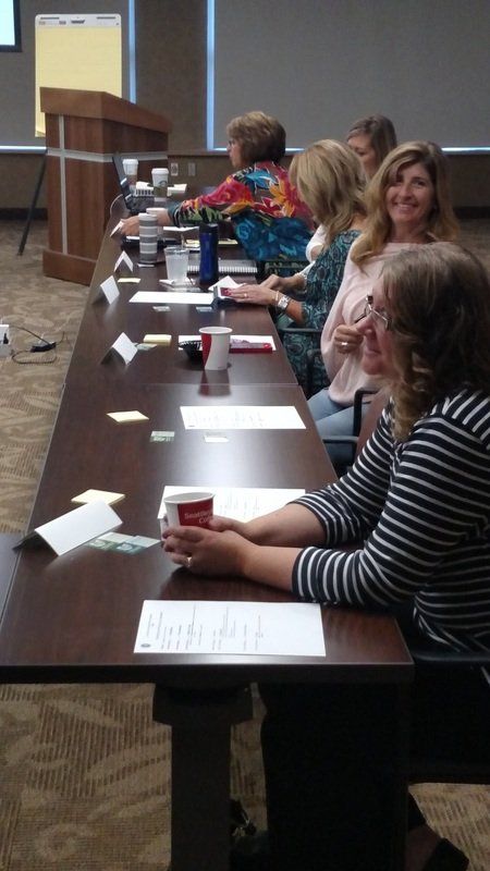A group of women are sitting at long tables in a room