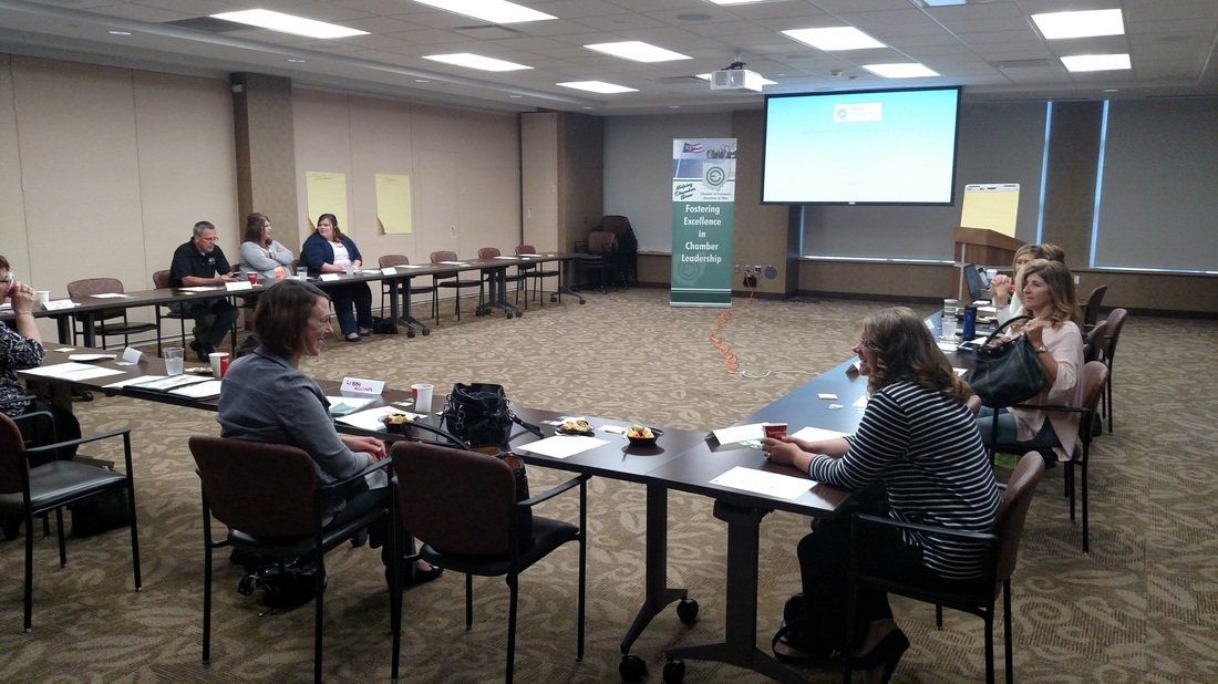 A group of people are sitting at tables in a conference room.