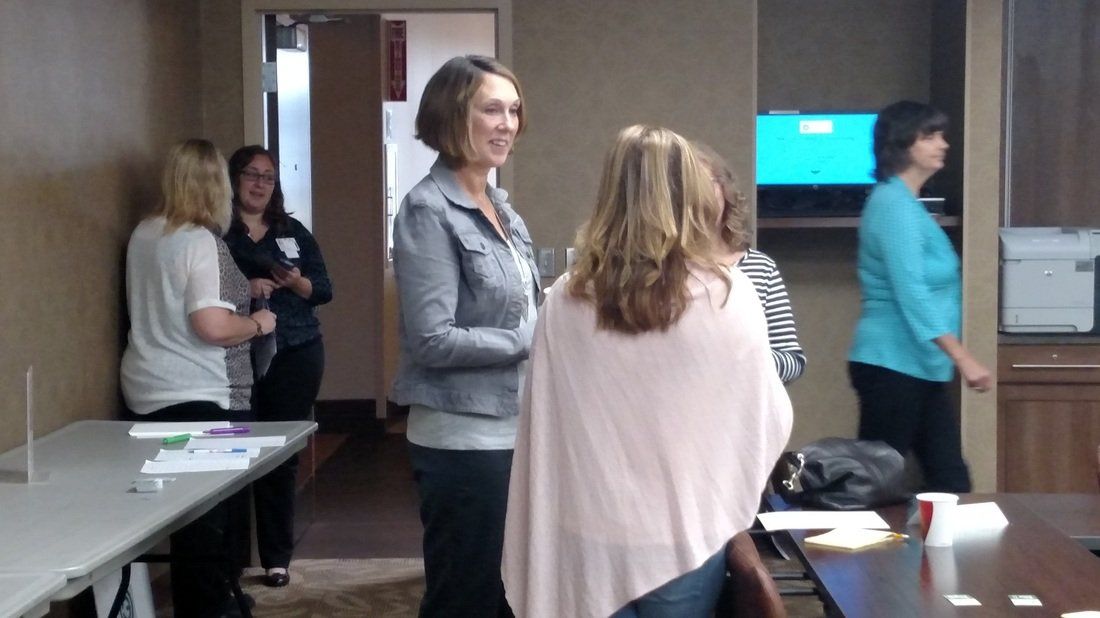 A group of women are standing in a room talking to each other.