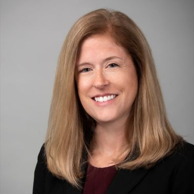 A bald man wearing glasses and a blue shirt is smiling for the camera.
