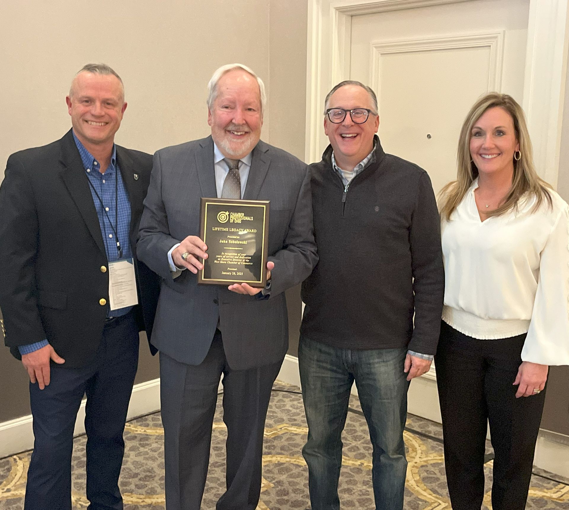 A group of people are posing for a picture and one man is holding a plaque