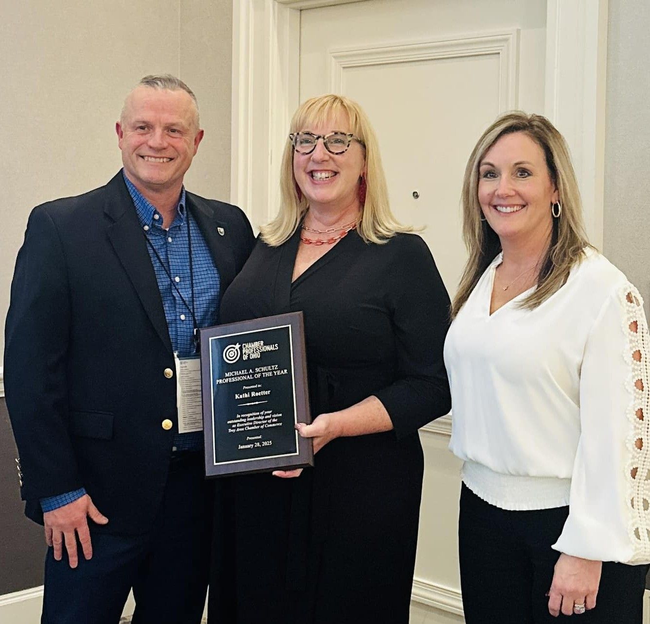 A man and two women are standing next to each other holding a certificate.