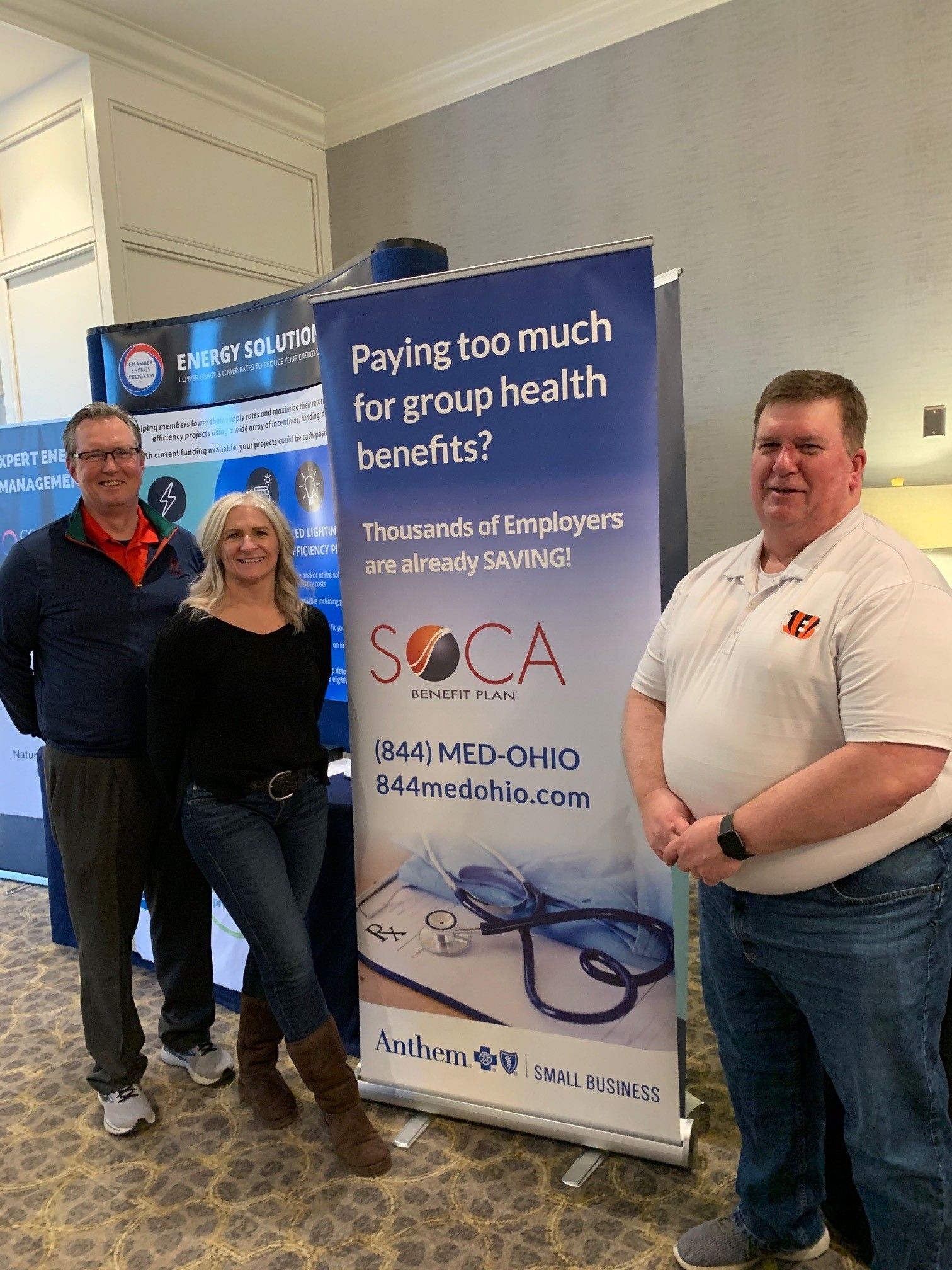 A group of people standing in front of a sign that says paying too much for group health benefits.