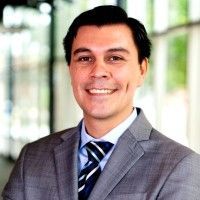 Man in a gray suit smiles, blurred background.