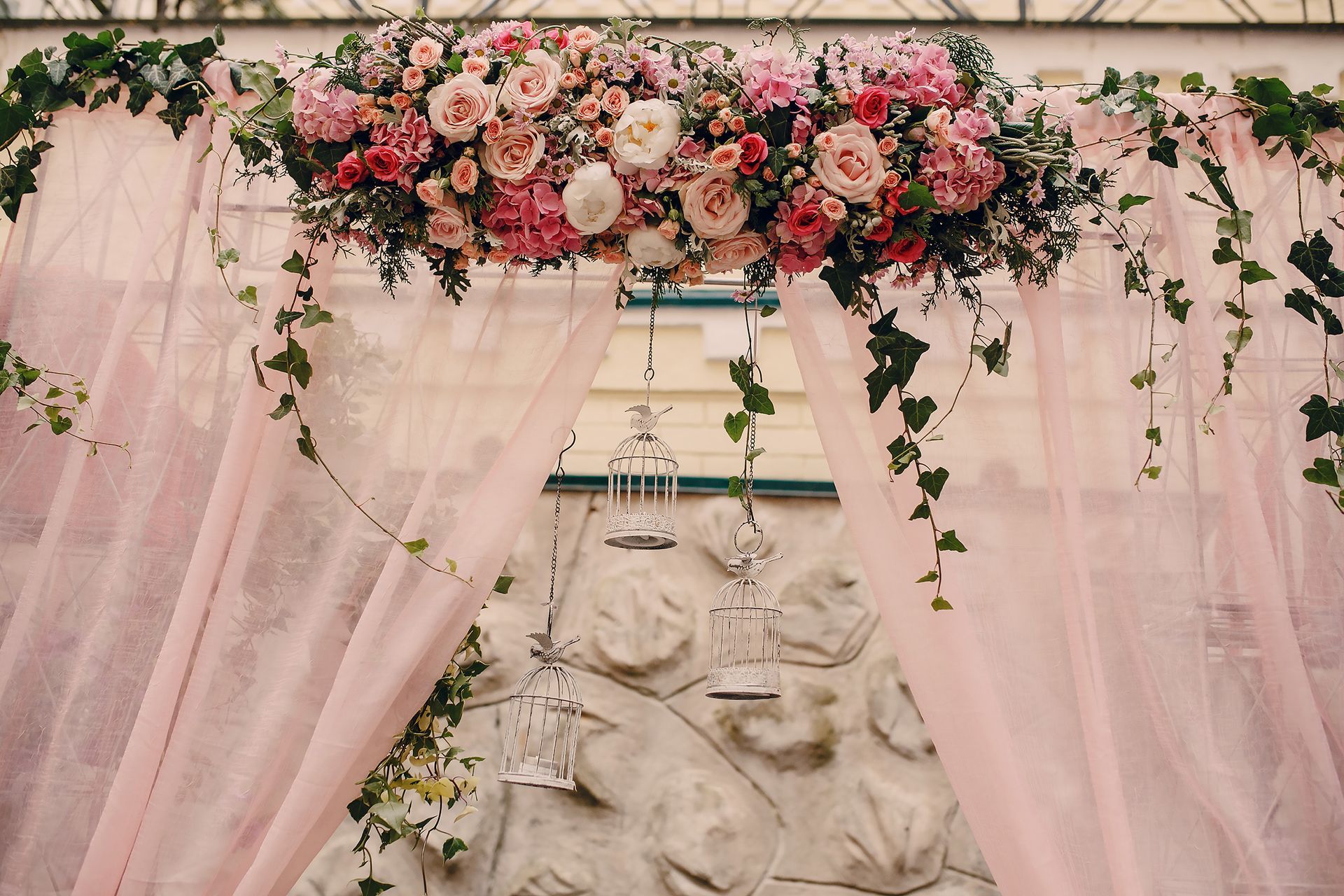 Una statua è circondata da tende rosa e fiori