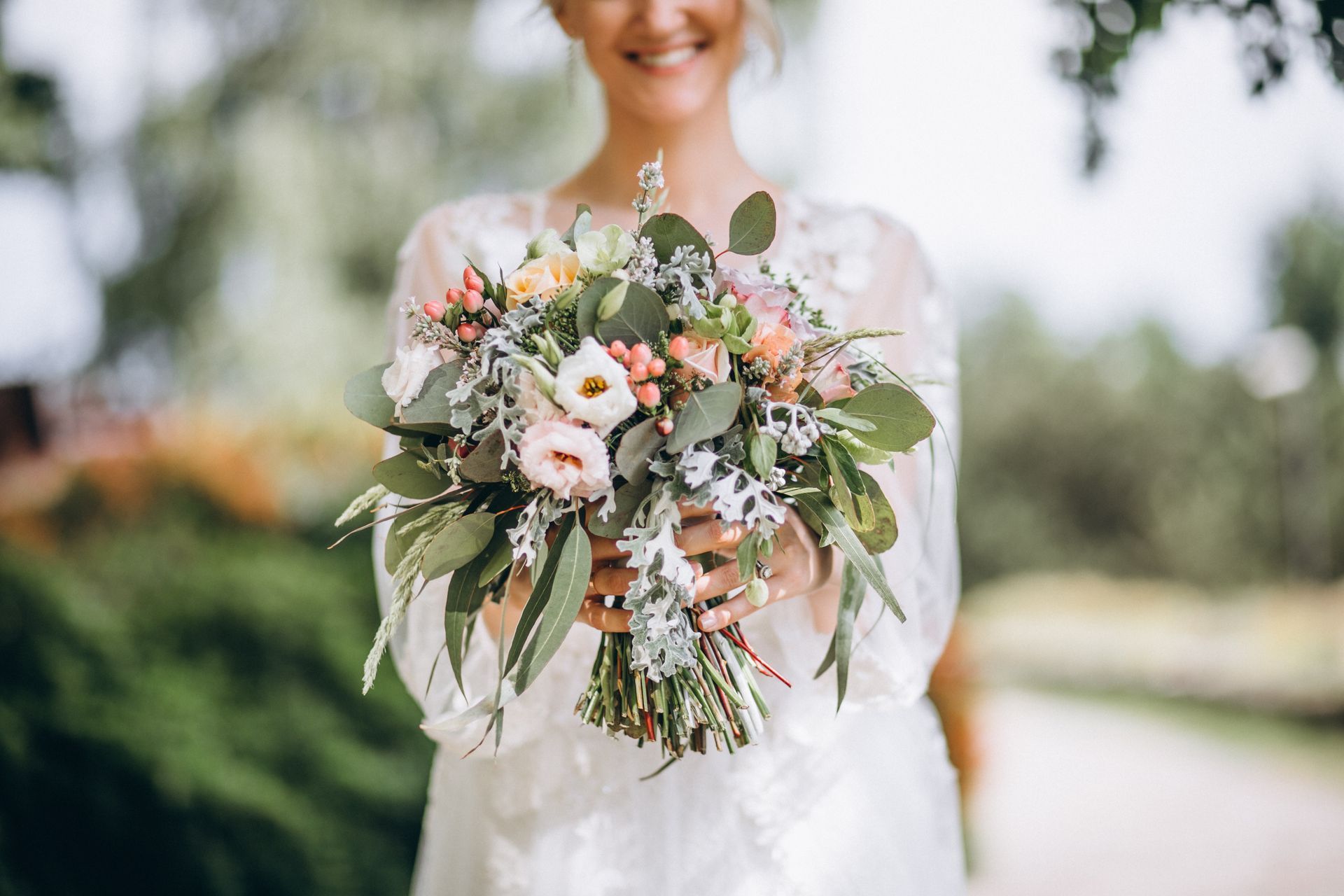Una sposa in abito bianco tiene in mano un mazzo di fiori.