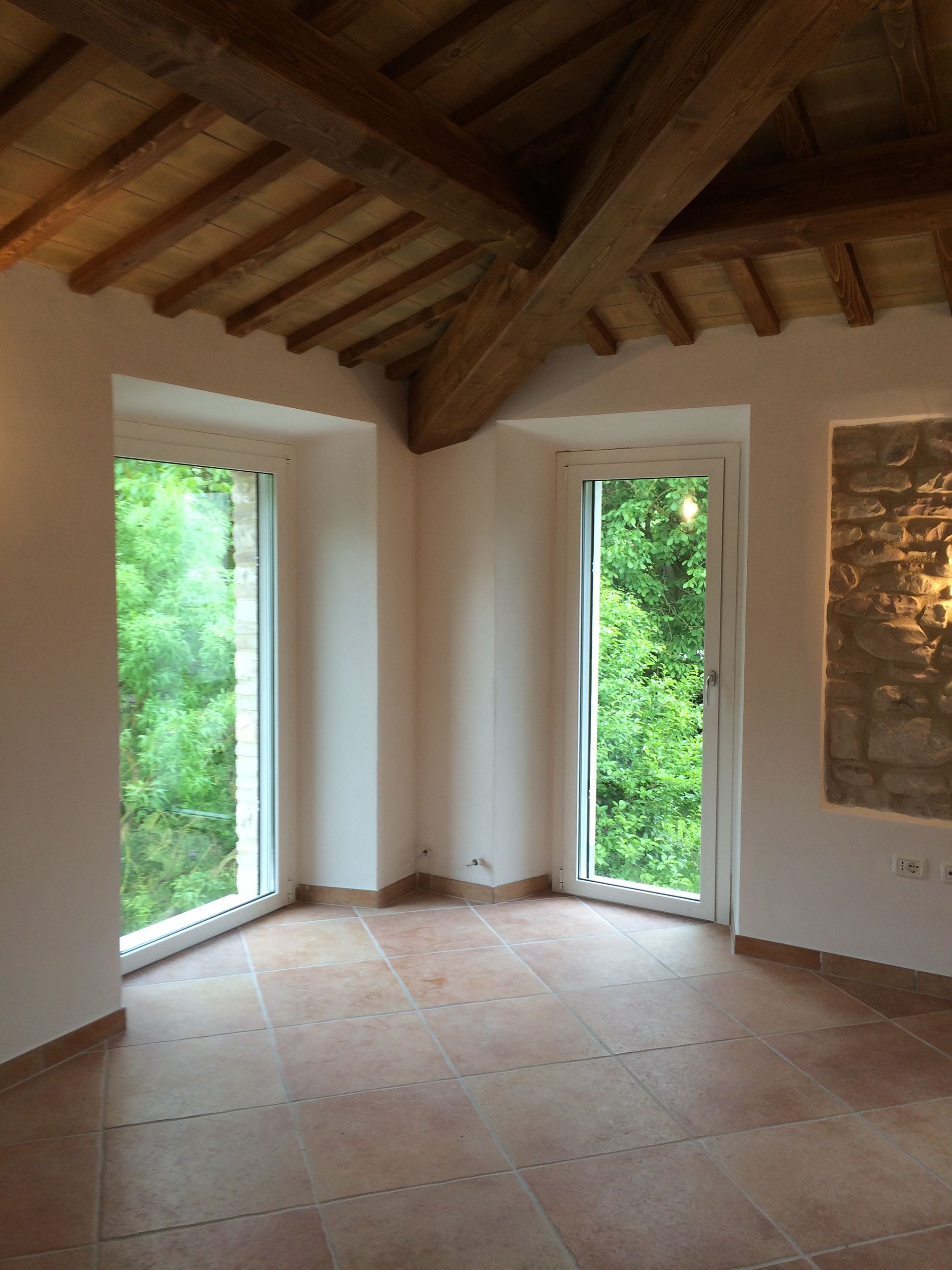 una stanza vuota con molte finestre e un soffitto in legno