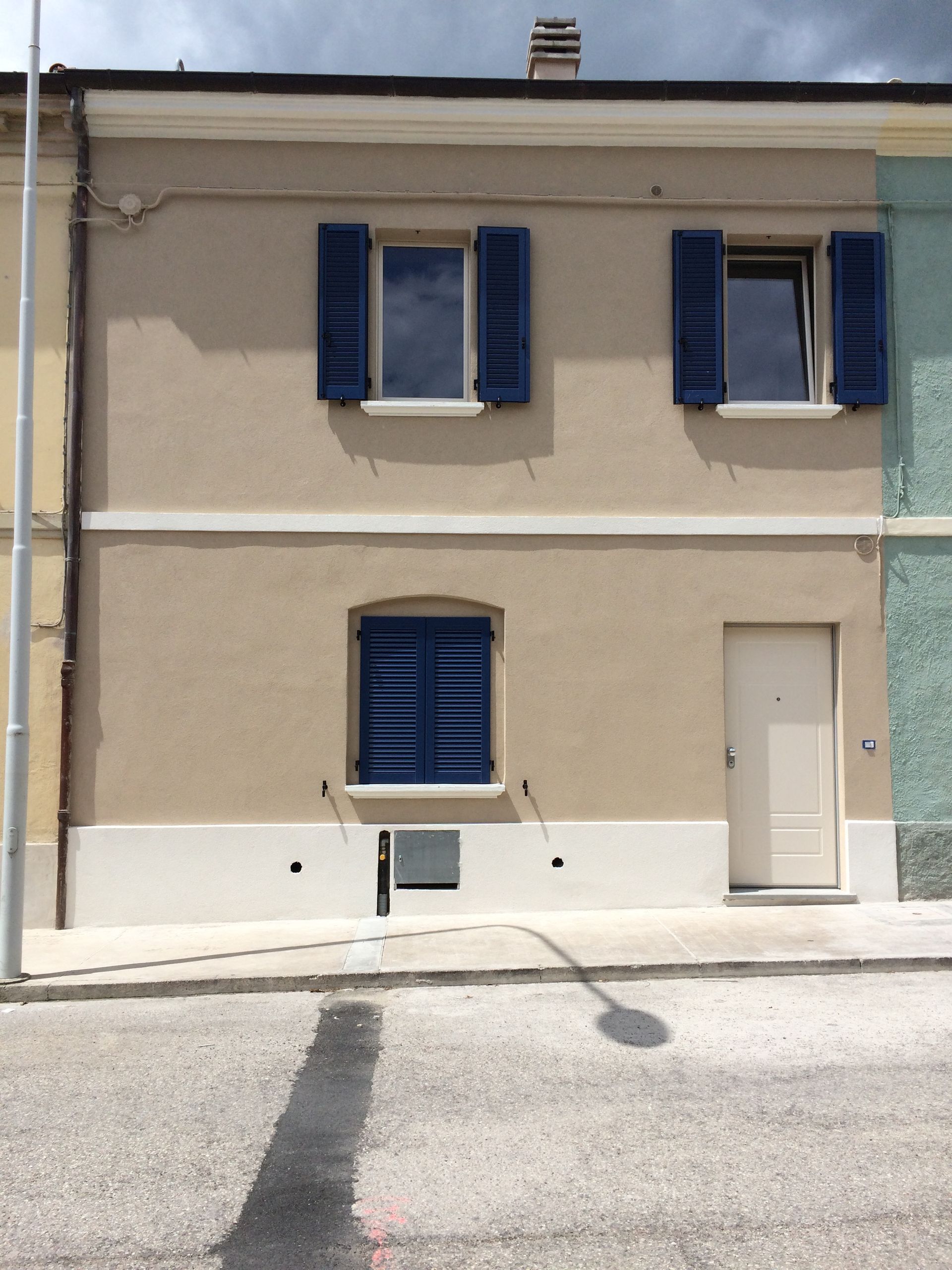 una casa con persiane blu e una porta bianca