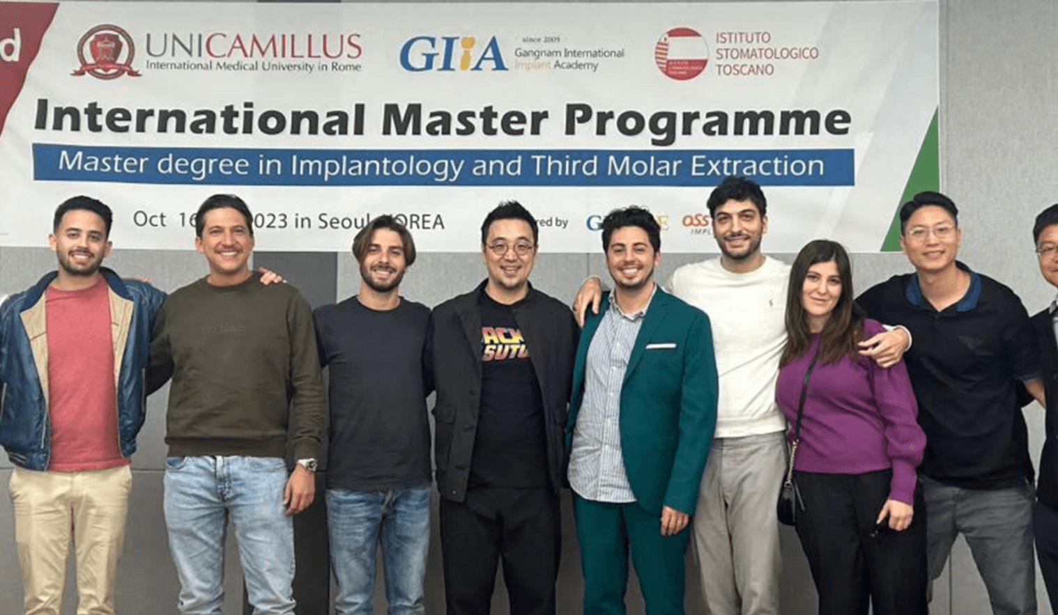 A group of people pose in front of a banner that says