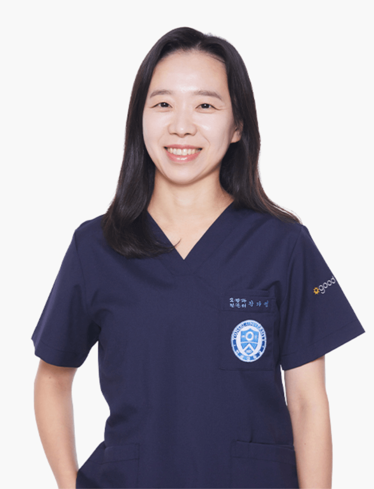 A smiling Asian woman wearing a navy blue medical uniform with a badge, against a white background.