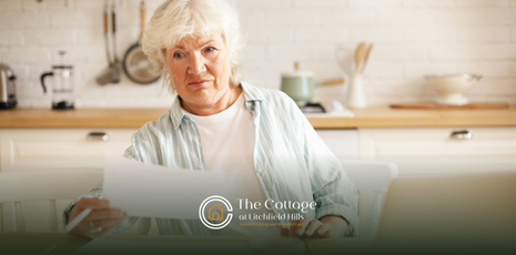 An elderly woman sitting at a table using a tablet