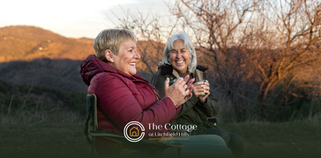 Two senior living residents happily talking together on a bench outdoors