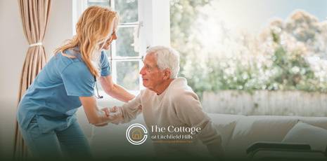An assisted living caregiver assisting an elderly man while standing up