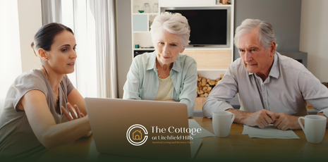 A woman is having the money conversation with her aging parents at a table, using a laptop