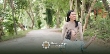 A caregiver kissing the head of an eldery person n a respite care facility