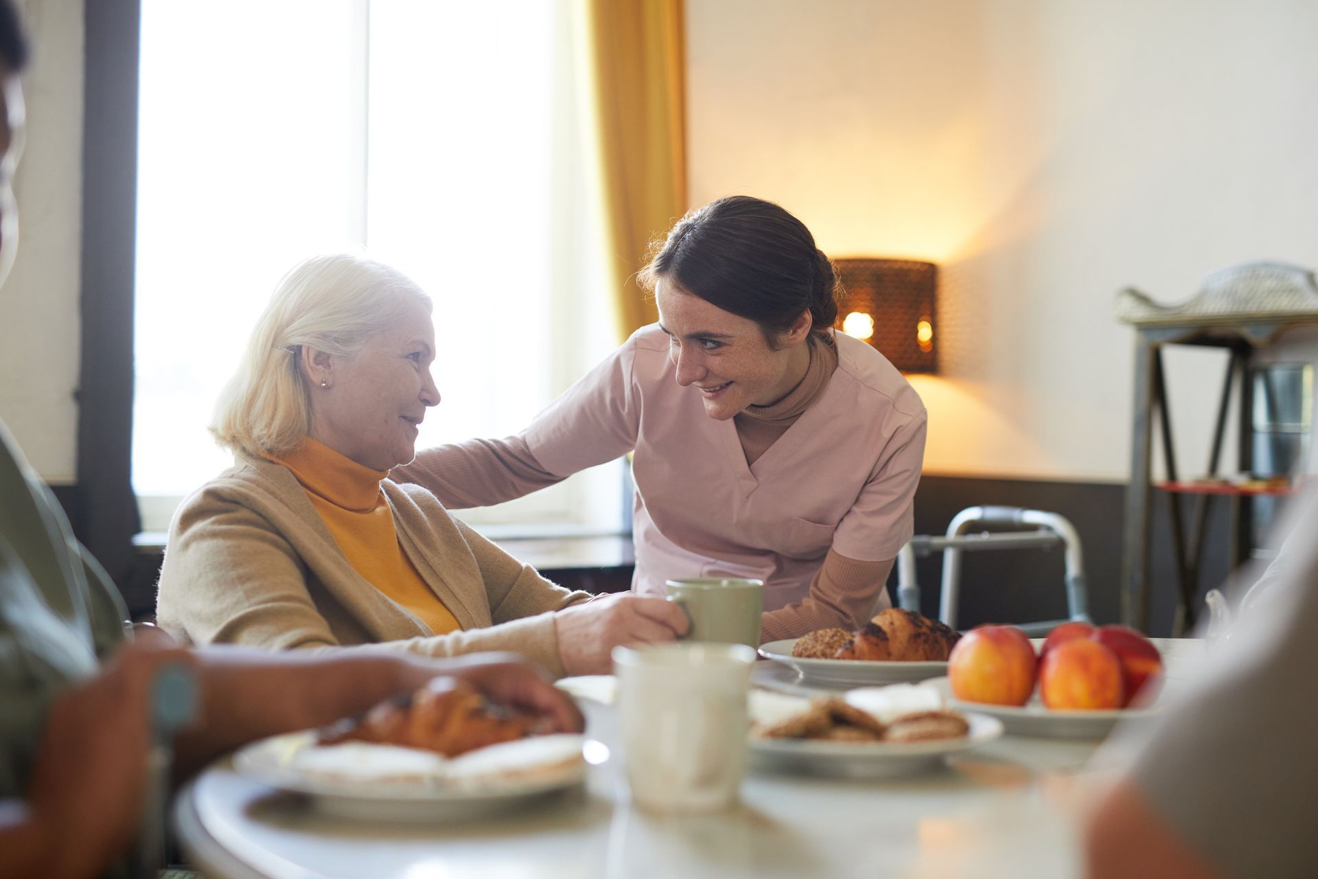 A nurse is talking to an elderly woman while sitting at a table.