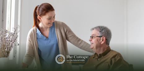 A caregiver is talking to an elderly man in a wheelchair