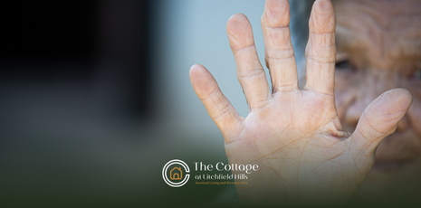 A hand with open palm, reaching forward. Skin is light with visible lines and wrinkles.