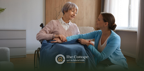 A respite care patient in a wheelchair smiles as a caregiver holds her hand.