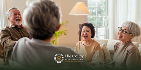 A group of residents is laughing together in a senior living facility
