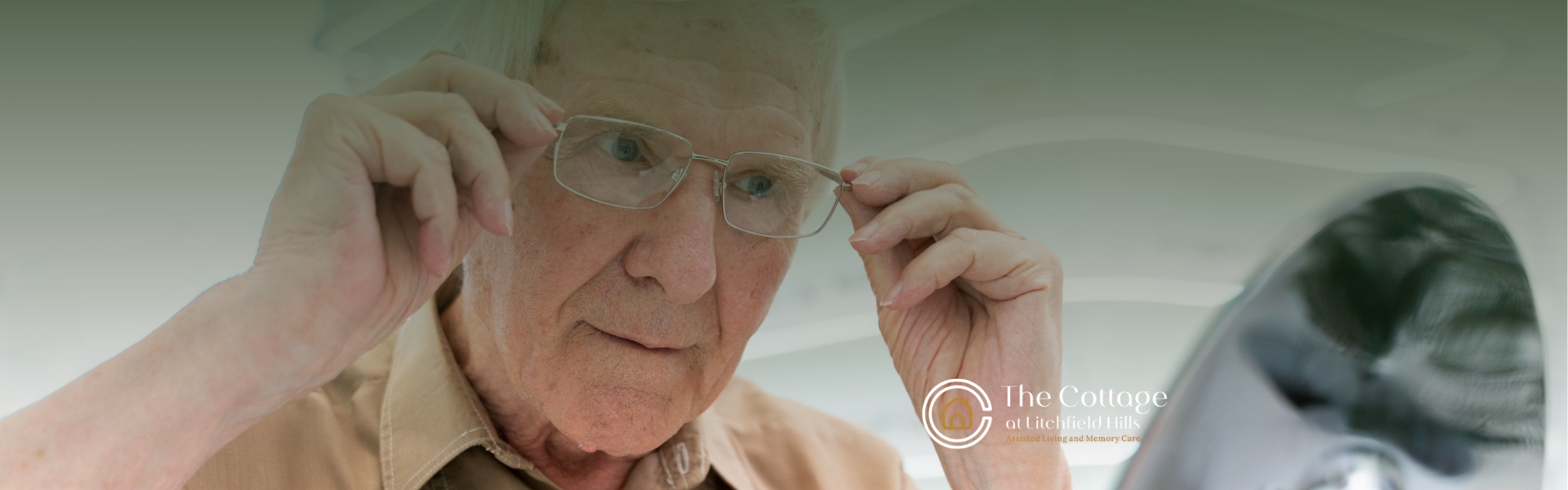 An elderly person wearing glasses, adjusting them with their hands.