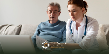 A senior and a medical professional sitting on a couch, looking at a laptop, reviewing costs