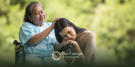 A daughter resting her head on her mother's lap with Alzheimer's disease.