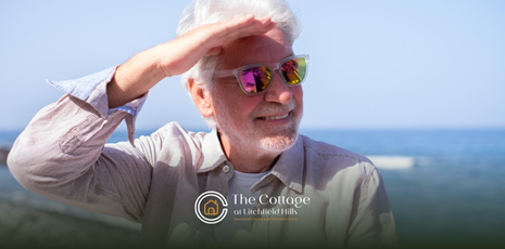 Elderly man in sunglasses shielding his eyes from the sun at the beach