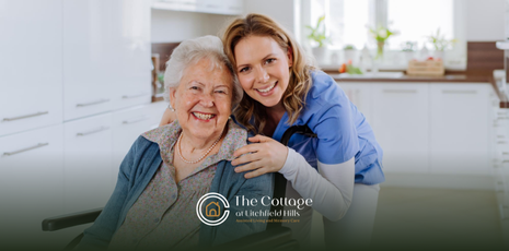 An assisted living staff member hugging a senior in a wheelchair