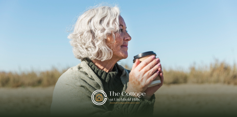 An elderly woman holding a coffee cup, outdoors, enjoying the day.
