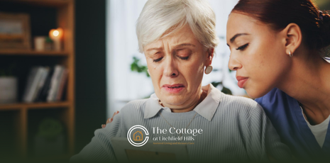 An older woman looking at a photo, comforted by a caregiver