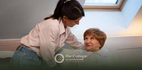 A caregiver is helping an elderly woman get out of bed in a senior respite care facility