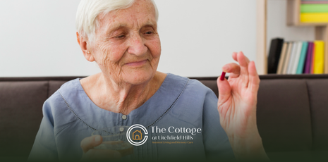 An elderly woman sitting on a couch holding a piece of a supplement