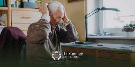 An elderly person holding his head with his heads, feeling anxious