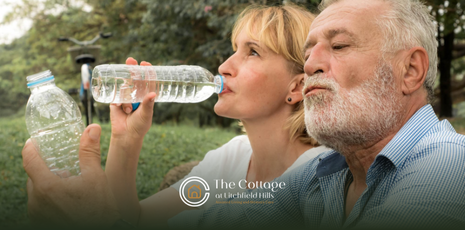 Two older adults are drinking a bottle of water