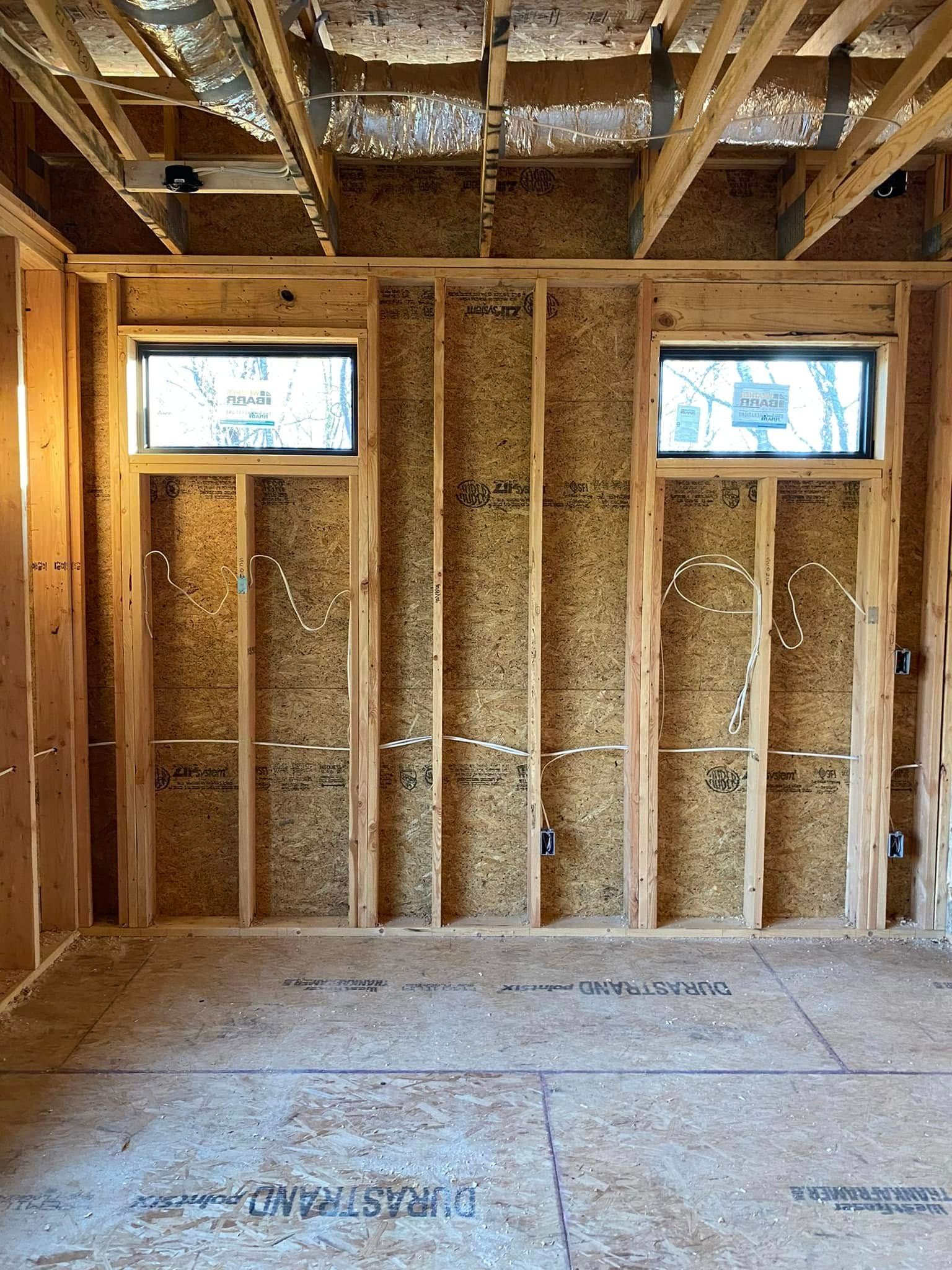 A room in a house under construction with wooden walls and windows.