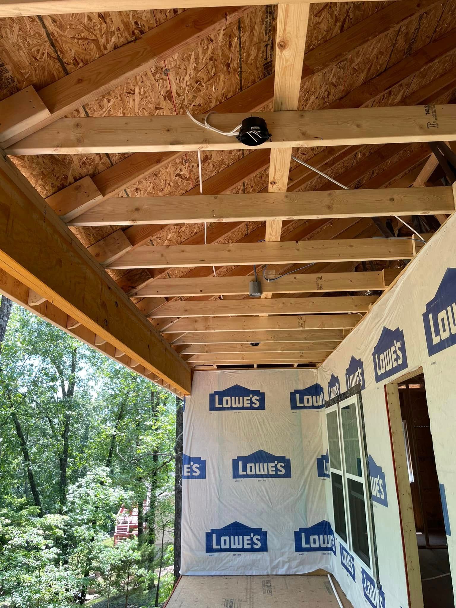 A building under construction with a lot of wooden beams and a wall that says lowe 's on it.