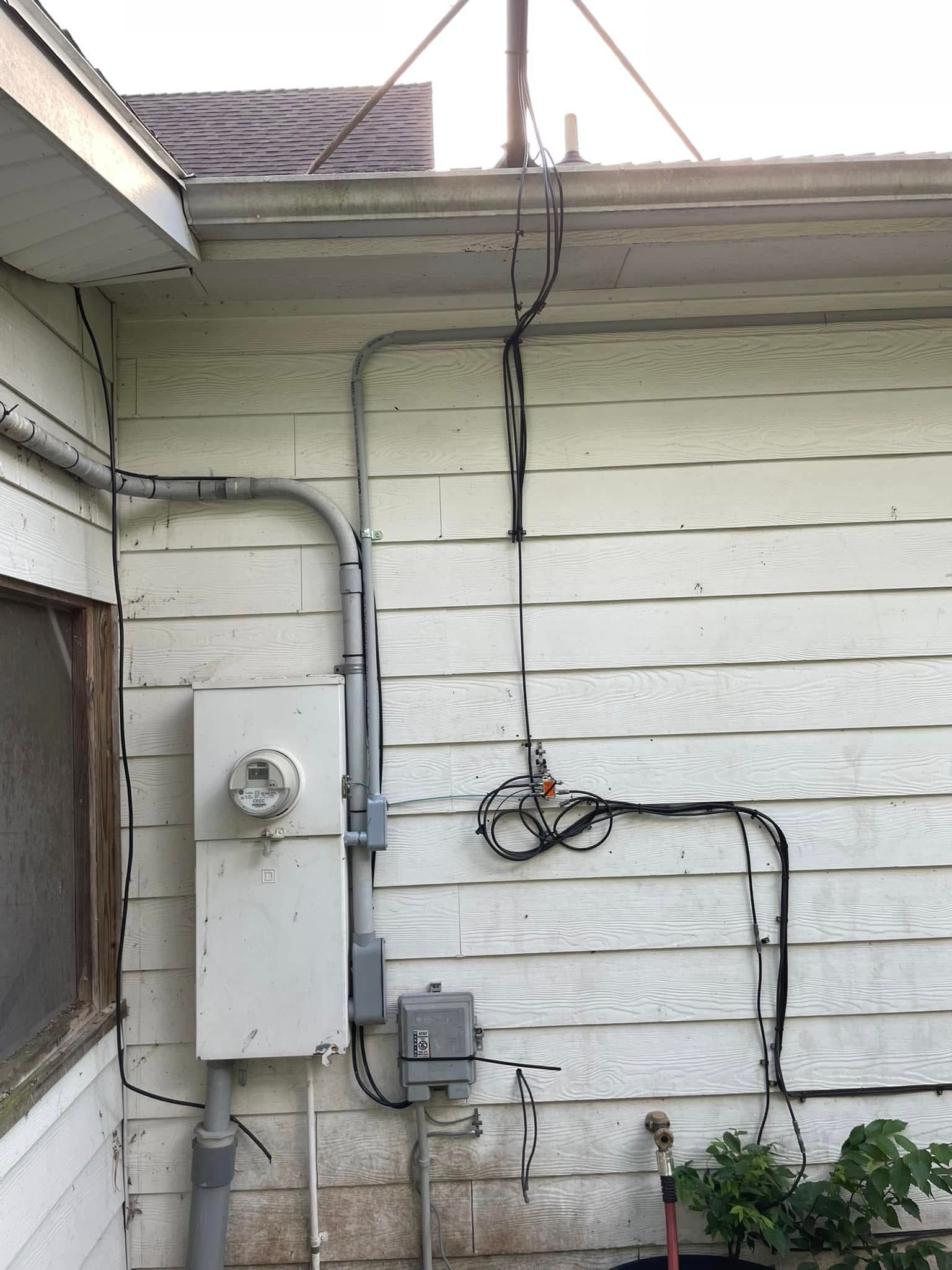 A white house with a lot of wires on the side of it.