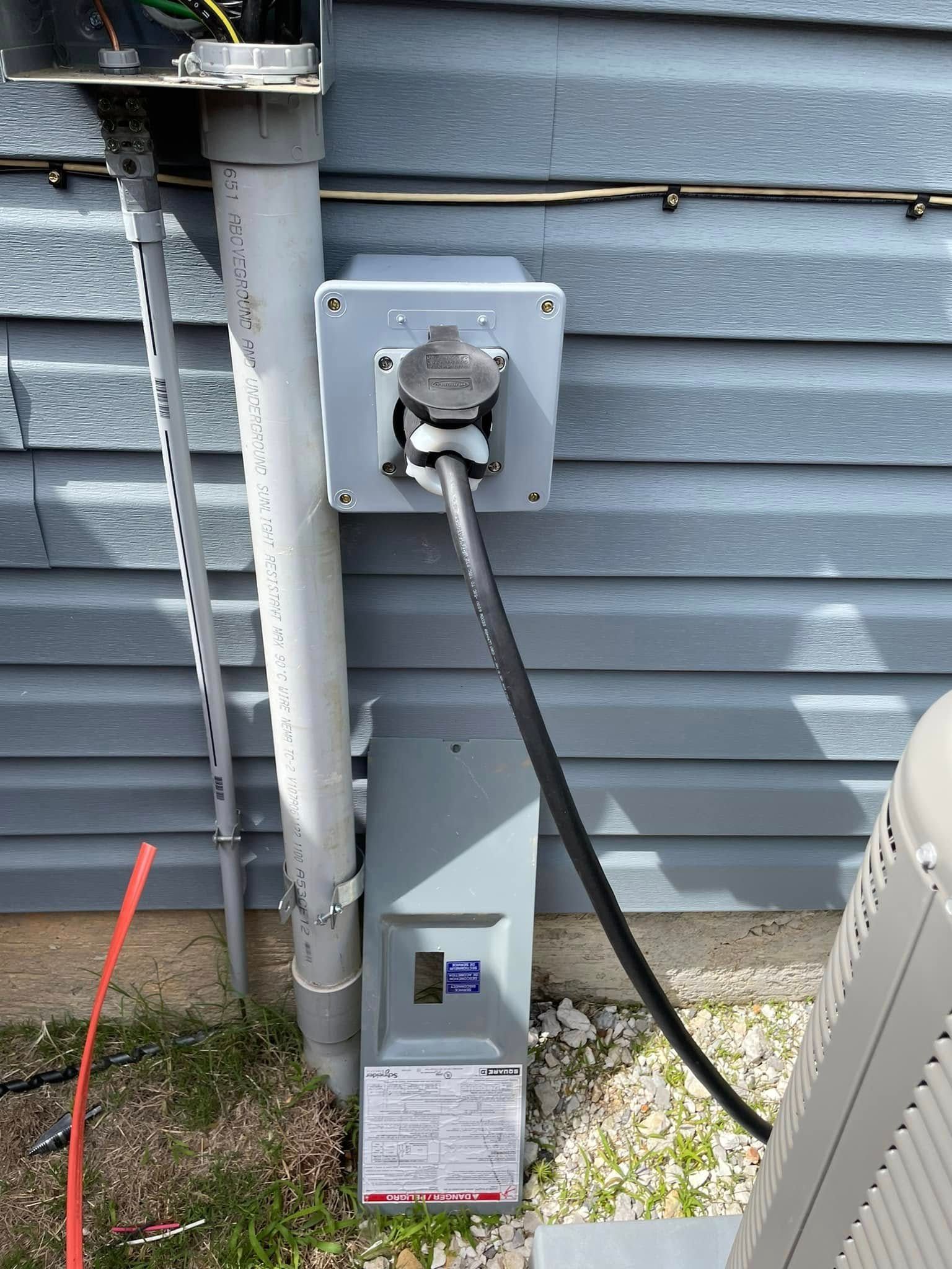 A power outlet on the side of a building next to an air conditioner