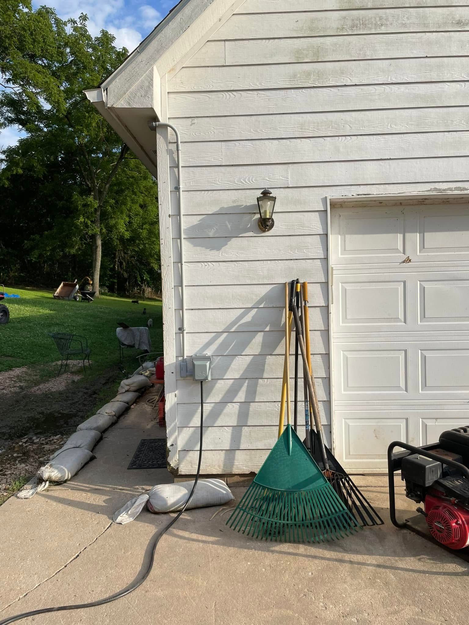 A bunch of gardening tools are sitting on the side of a garage.