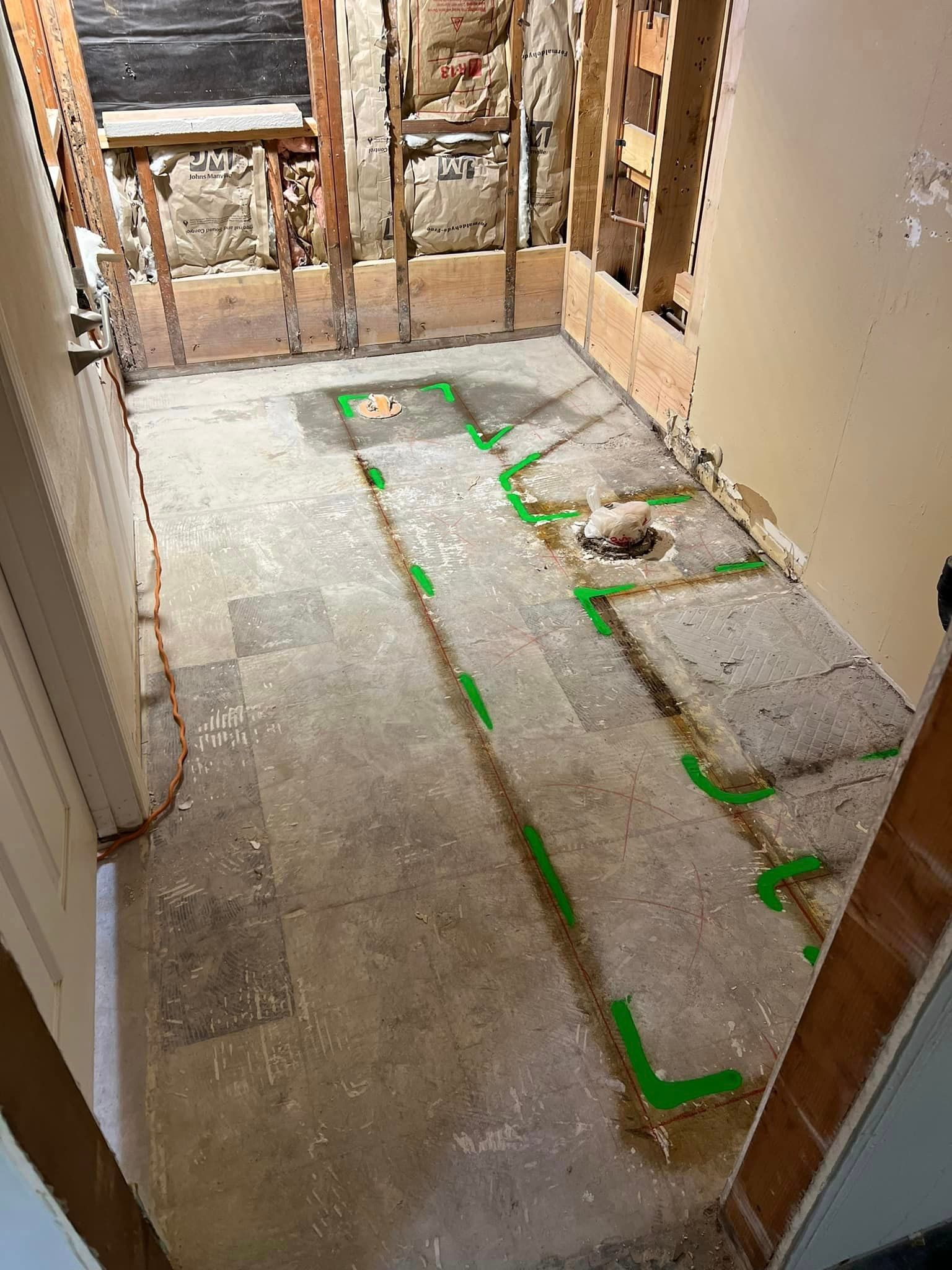 A Bathroom Under Construction With Green Tape On The Floor - San Diego, CA - Acadia Design & Construction