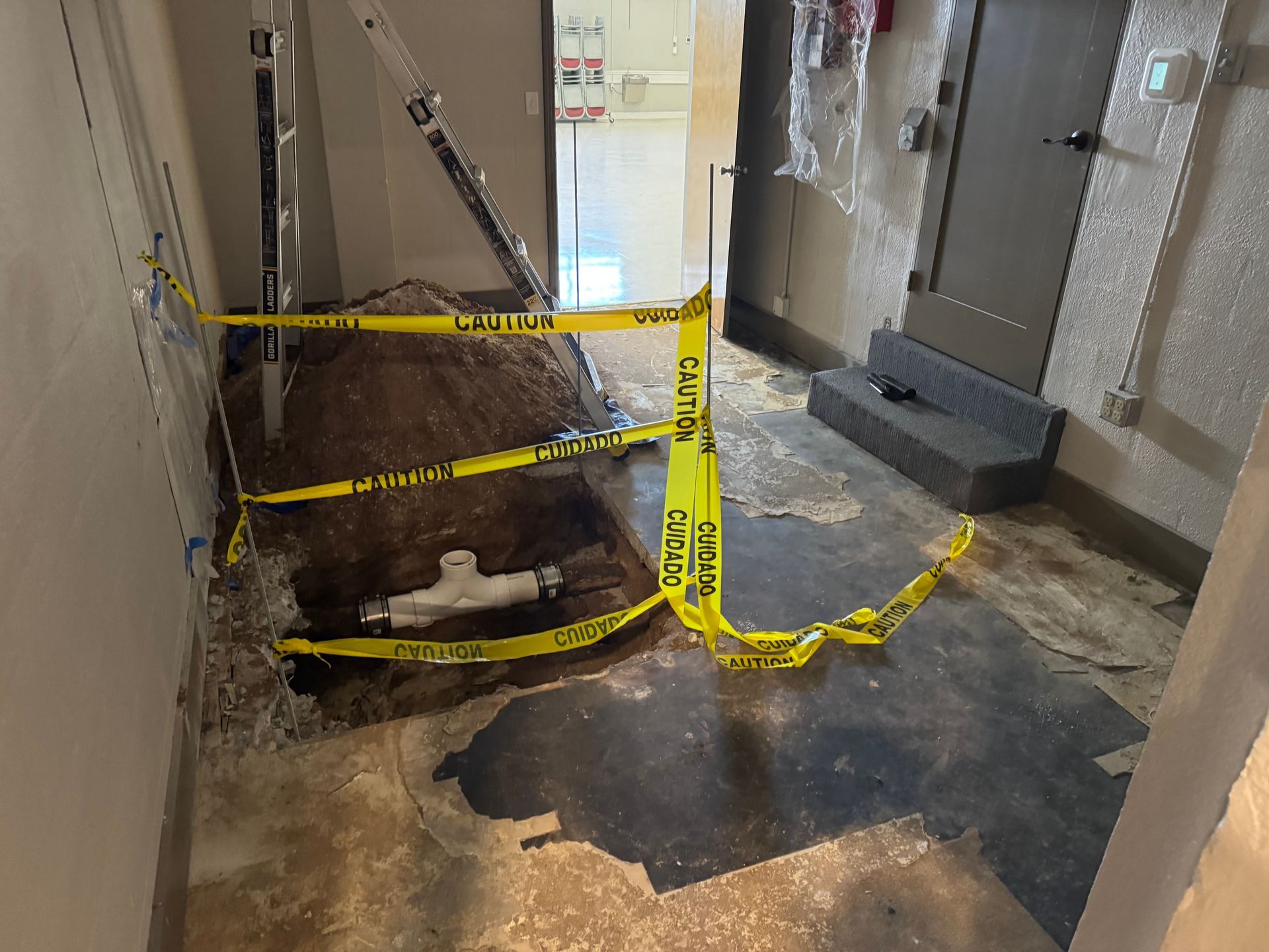 Yellow caution tape blocks a large floor hole in a dim hallway