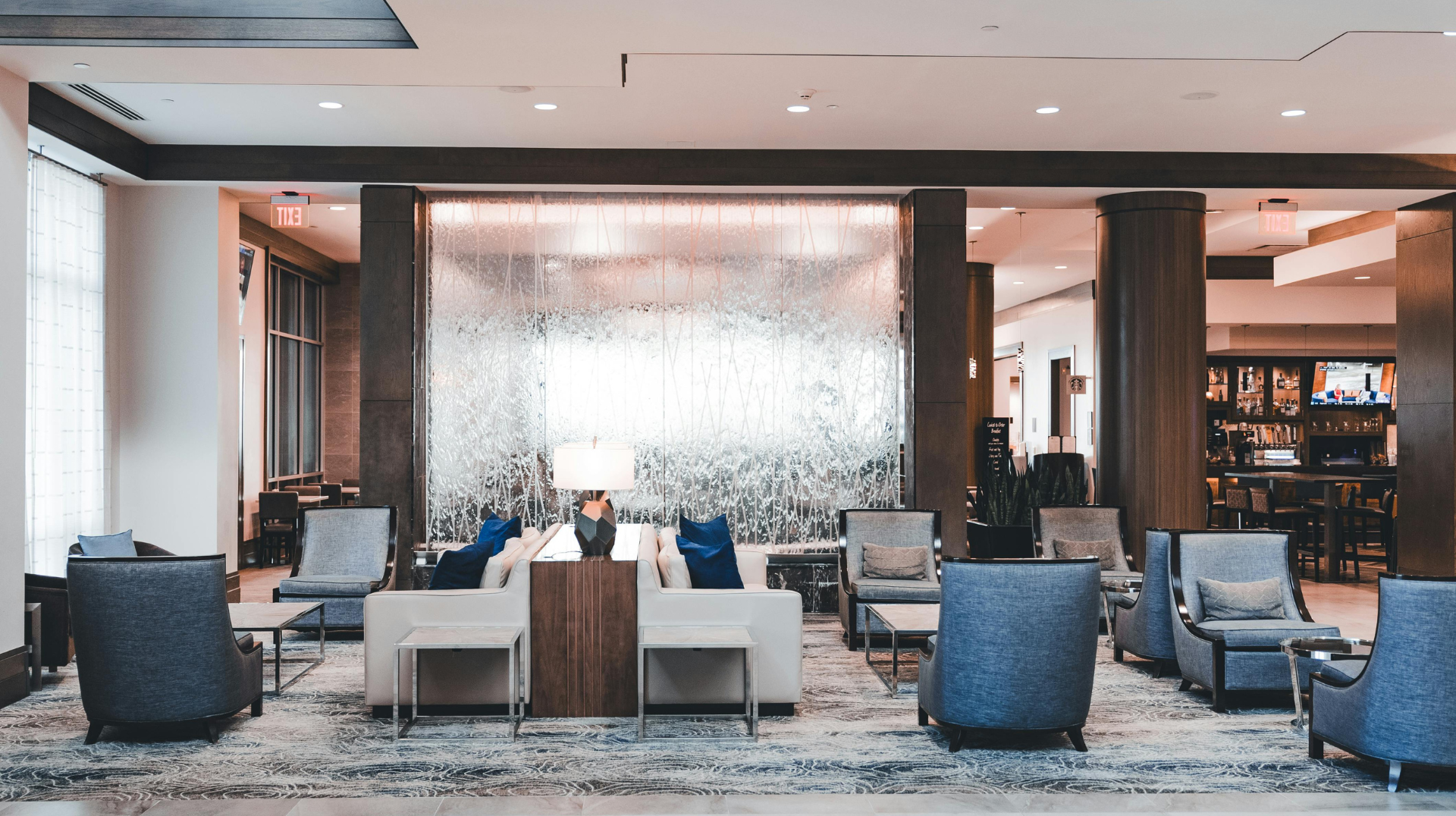Empty, sunlit room with hardwood floors, large windows, and white walls.