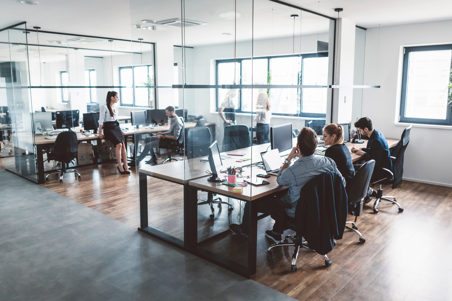 Spacious, modern living area with light wood floors, a staircase, and open kitchen.