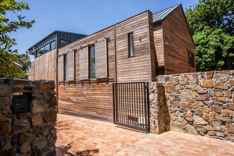 A wooden house with a stone wall and a gate in front of it. 7 Lemon Lane – Newlands